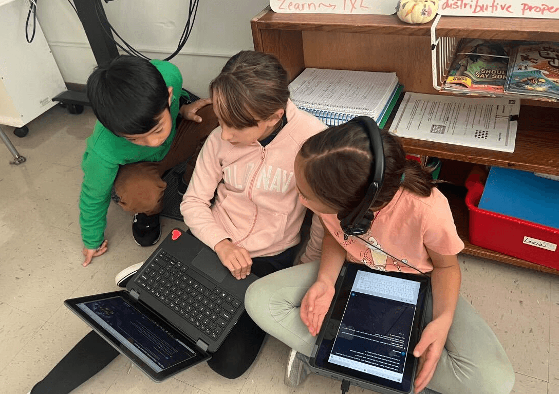 Students using SchoolAI on laptops, huddled around each other